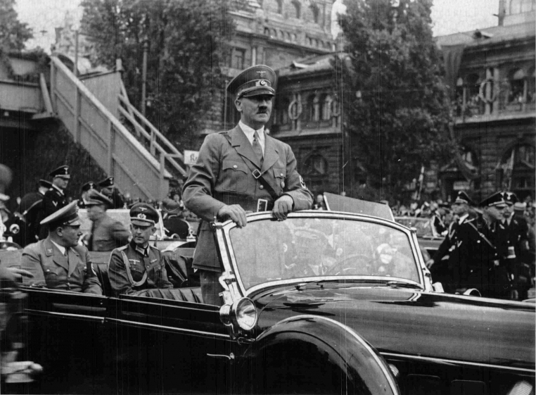Hitler standing in his car as he travels through the ancient town of Nuremberg to open the Party Congress